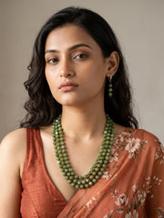 Close-up of square and cube-shaped olive green beads separated by smaller dark green spacer beads, showing the texture of the layered strands