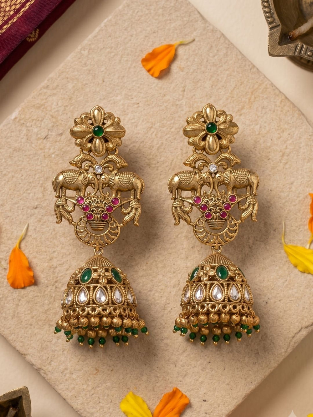 Elephant design temple jhumka earrings in antique gold with Kundan Polki stones, green synthetic gemstones and ornate traditional detailing