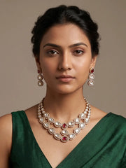 Gold finish ruby Polki necklace and earrings set with oval and teardrop stone motifs, layered detailing and a coordinated traditional design