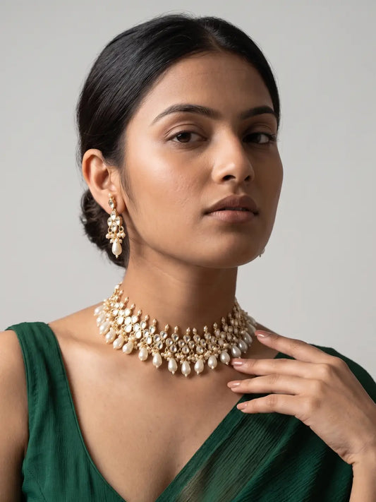 Gold plated Kundan Polki choker necklace with intricate stone detailing, pearl drops and matching earrings for bridal and festive wear.