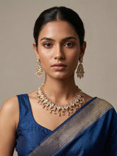 Woman wearing a blue saree with gold-plated peacock-design polki jewelry set against a neutral background
