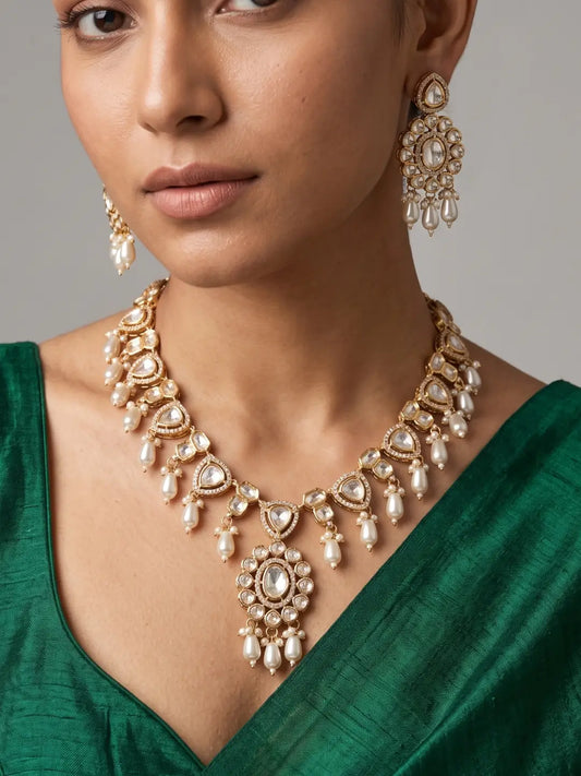 Gold plated Polki necklace with teardrop stones, intricate detailing, pearl drops and matching earrings for wedding and festive wear.