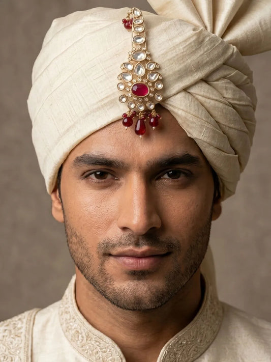 Groom wearing a gold plated red Kundan Polki kalangi pinned to a traditional wedding safa.