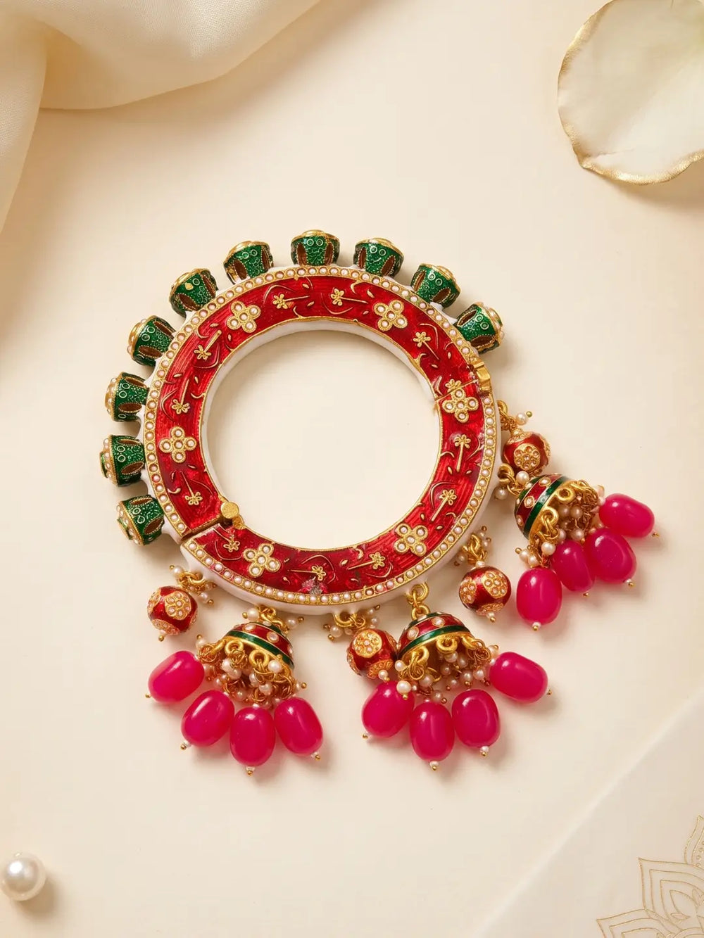 Gold plated red Meenakari Pacheli kada featuring Kundan-style stones, synthetic pearls and hanging bead details for traditional wedding styling.