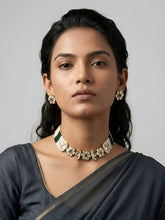 a women wearing delicate green stone kundan and pearl choker necklace set