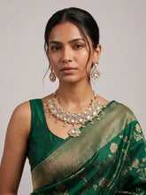 A women wearing an Elegant Gold Plated Wedding And Bridal Wear Kundan Necklace Set on a green saree