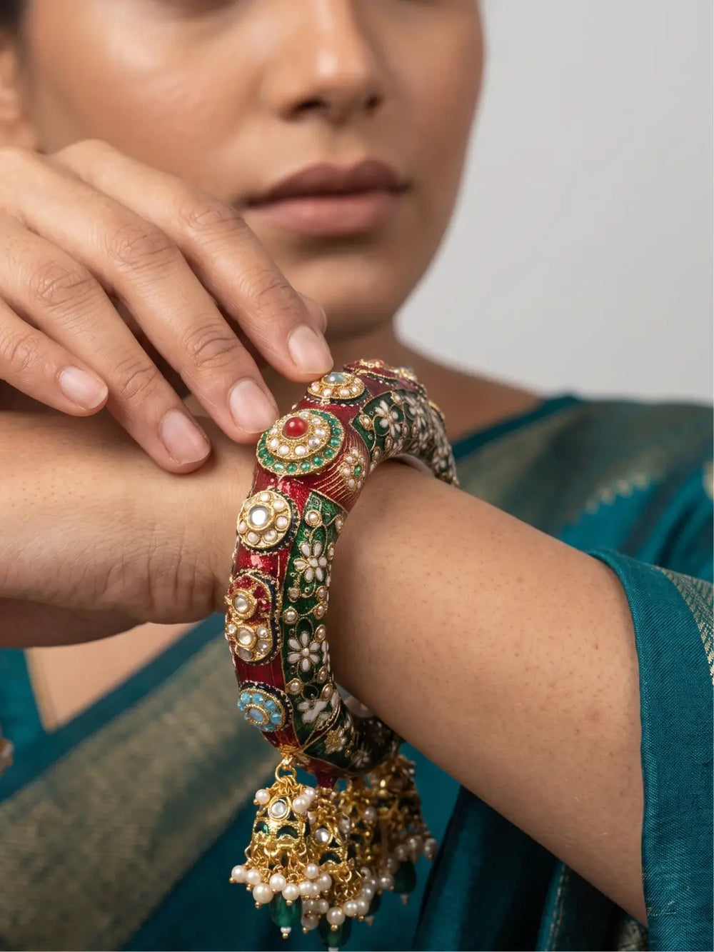 Green Kundan Meenakari bridal kada with cascading jhumka and bead drops, featuring gold plating and ornate detailing for wedding outfits.