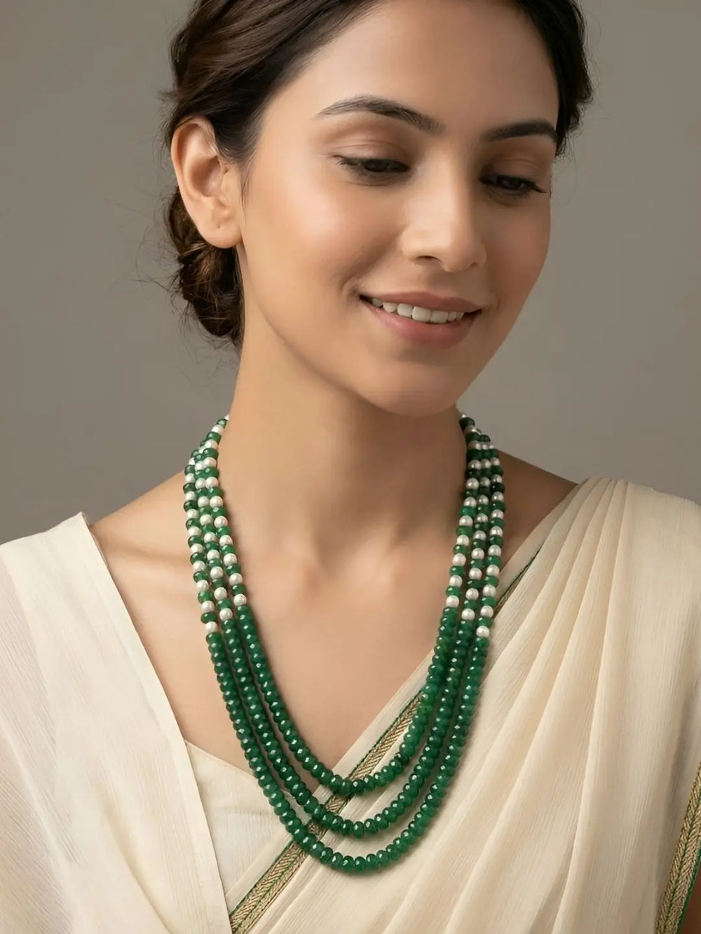 Green and red jade beaded mala featuring multiple strands of shell pearls and gold-plated detailing for saree and ethnic jewellery styling.