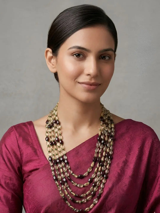 Woman wearing a layered natural gemstone necklace featuring warm yellow Citrine, deep Garnet and green Jade beads arranged in flowing strands for an elegant ethnic look.