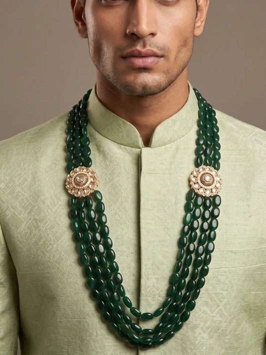 Long green groom necklace featuring multiple oval jade bead strands and symmetrical floral Kundan brooches with stone detailing
