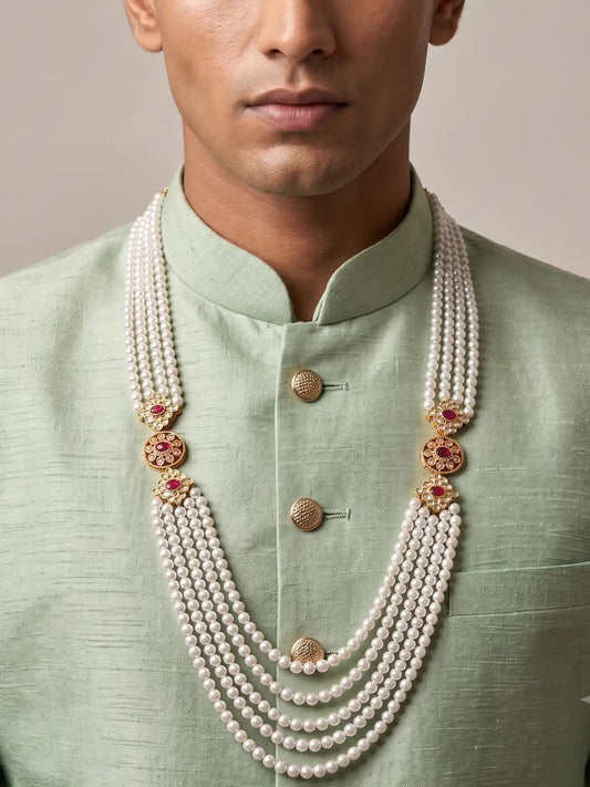 Layered white shell pearl groom mala with ornate gold-tone Kundan brooches and deep red stone accents for sherwani styling
