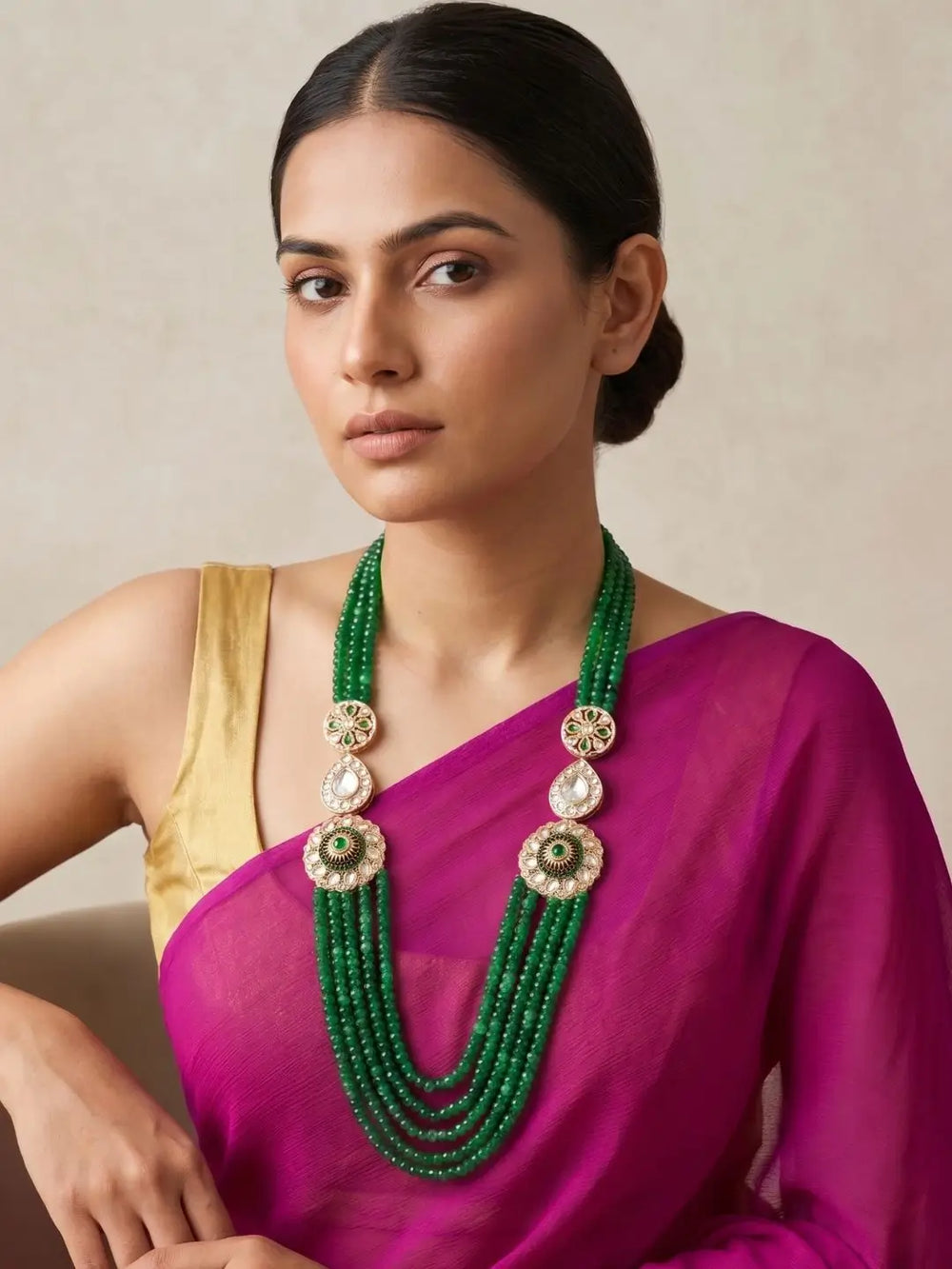 Long green jade beaded necklace featuring layered strands, floral Kundan-style brooches and white stone accents for Indian wedding outfits.