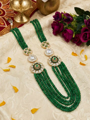 Long layered green Kundan necklace with jade beads, Polki-style floral brooches and white stone accents, designed for bridal and festive looks.