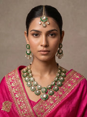 The accompanying maang tikka completes this green jewellery set, coordinating with the necklace and earrings through floral and teardrop motifs.