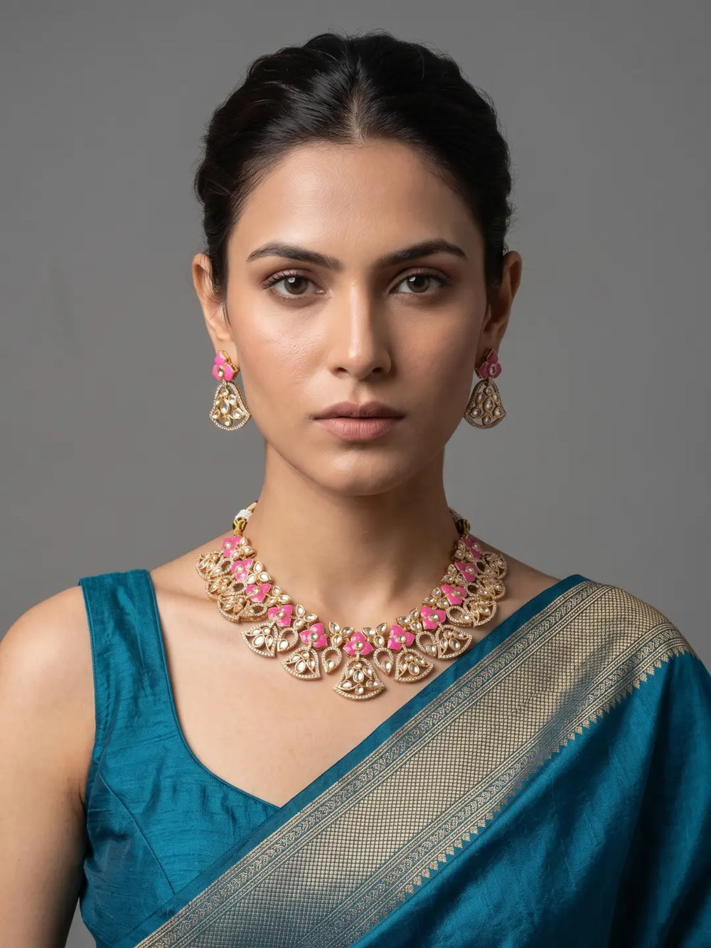 Woman wearing a pink floral Kundan necklace set featuring enamel accents, sparkling Polki and CZ stones, gold-plated floral motifs and matching earrings.