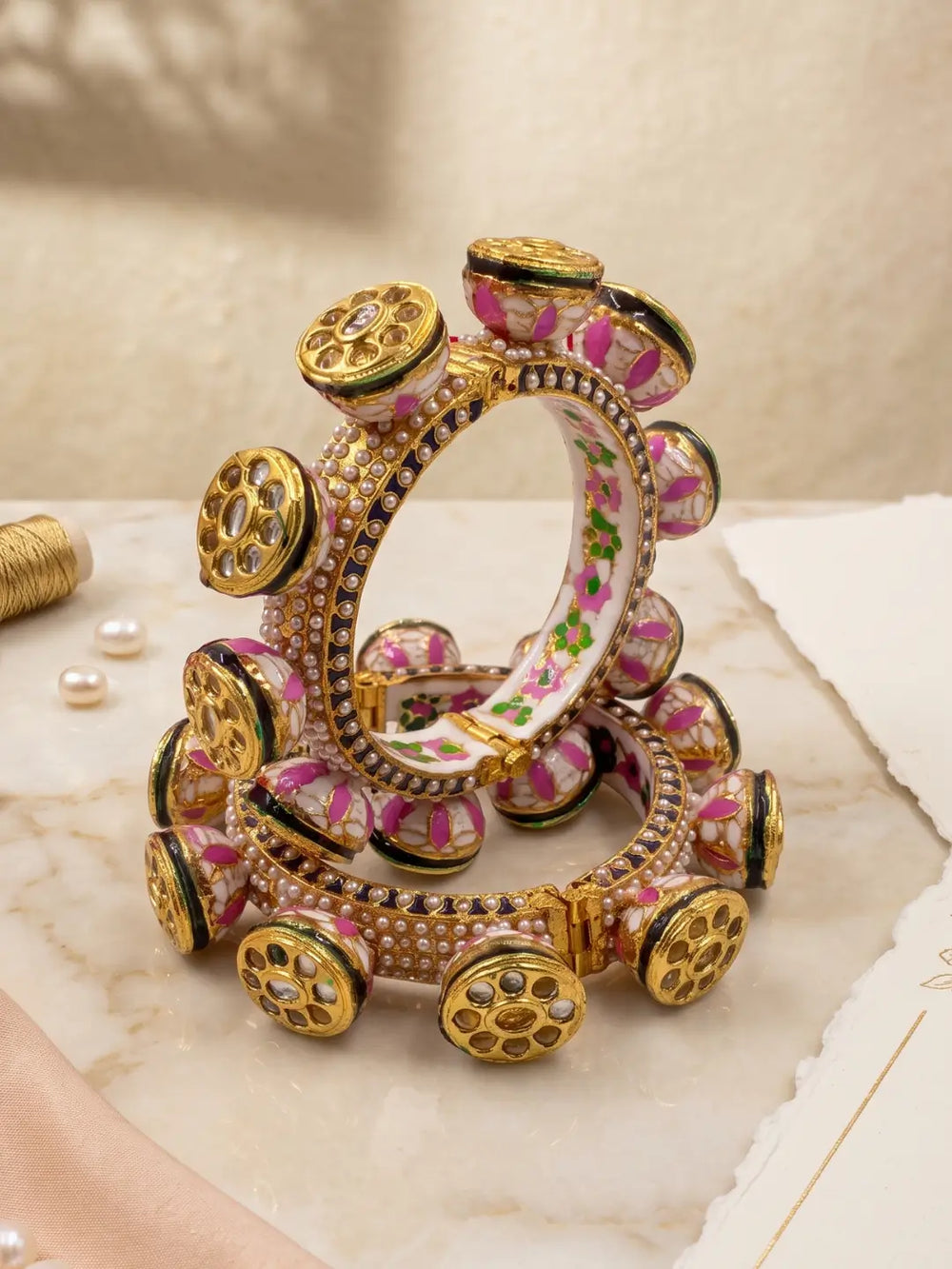 Pink and green Meenakari Kundan Pacheli kada bangles featuring multiple rows of pearl accents and floral detailing for wedding and festive looks.