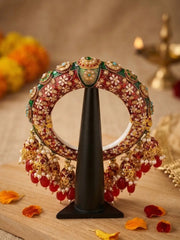 Red Kundan Meenakari bridal kada with cascading jhumka and bead drops, featuring gold plating and ornate details for wedding outfits.
