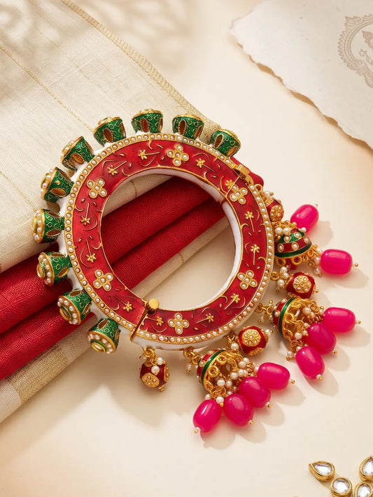 Red Kundan Meenakari Pacheli kada bangle with pearl accents, floral details and jhumka drops, designed for bridal and festive outfits