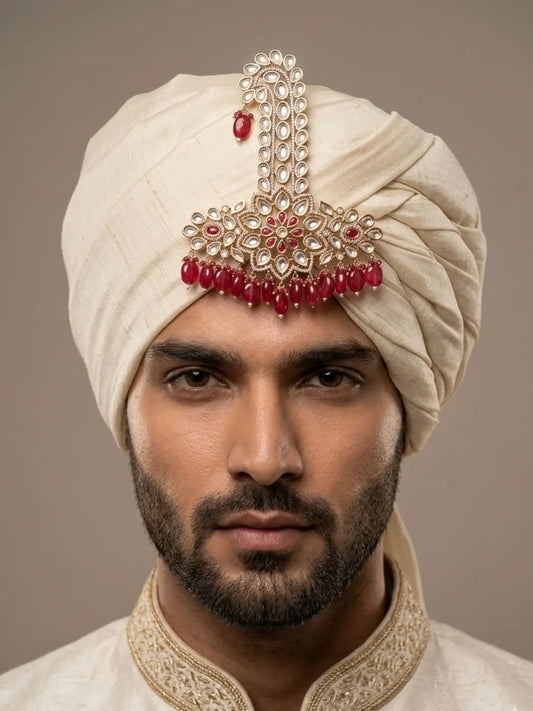 Groom wearing a red maharaja polki kalangi pinned to a safa turban