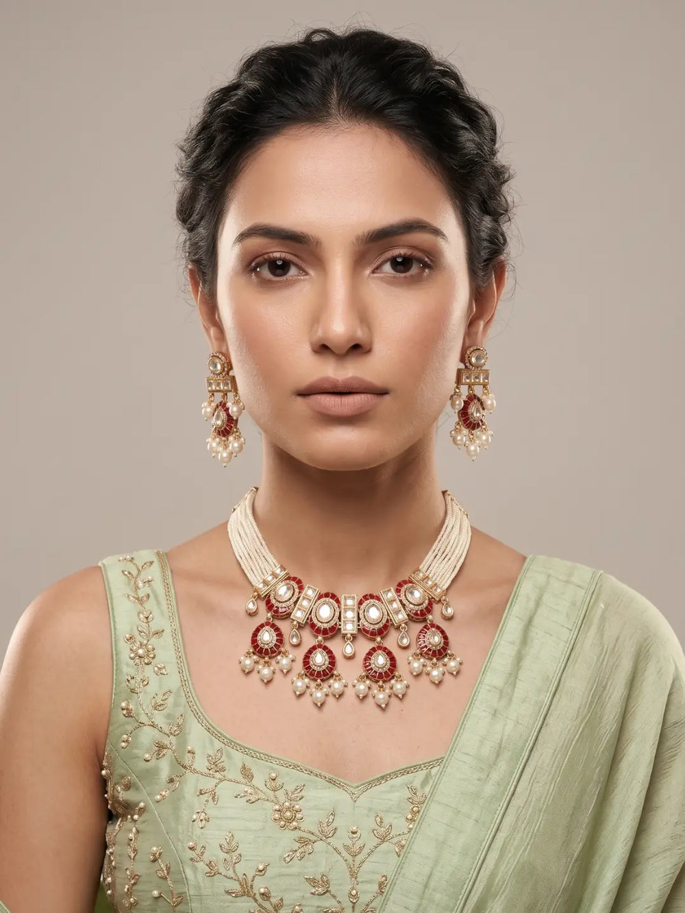 Close view of a woman wearing a red Polki choker with pearl accents, red Meenakari work, Kundan-inspired detailing and matching earrings for festive Indian styling.