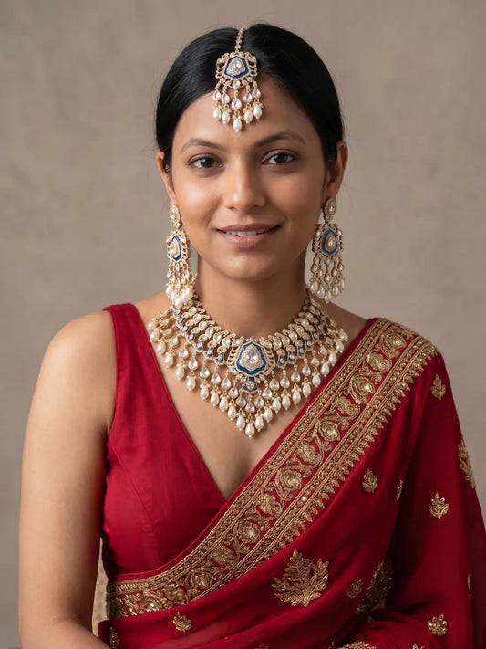 Bride wearing a royal blue Kundan bridal necklace set with Polki detailing, pearl drops, matching statement earrings and coordinating maang tikka for a traditional wedding look.