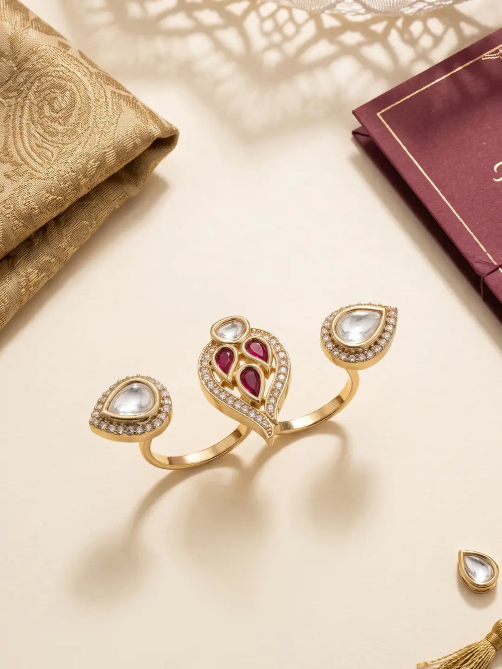 Ruby pink CZ and Polki-style double finger ring with gold plating and pear-shaped motifs, styled for wedding and festive outfits.