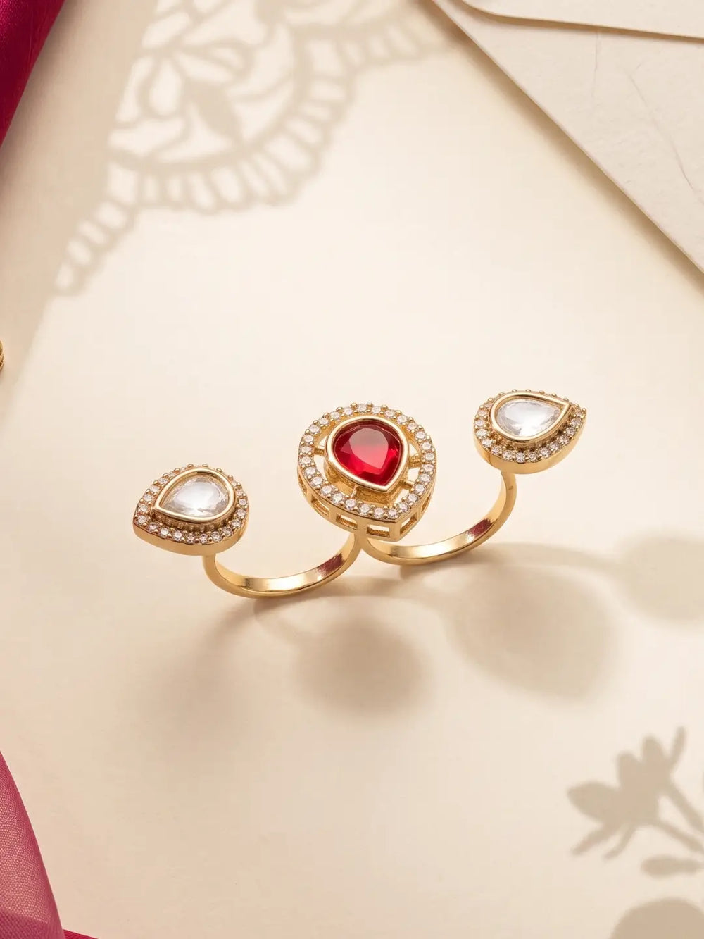 Ruby pink Kundan Polki dual finger ring with gold plating and pear-shaped CZ details, designed as a statement accessory for wedding outfits.