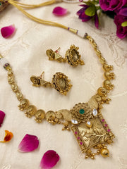Close view of the short gold plated necklace showing ornate floral motifs, vibrant coloured stones and delicate pearl detailing in antique gold tone