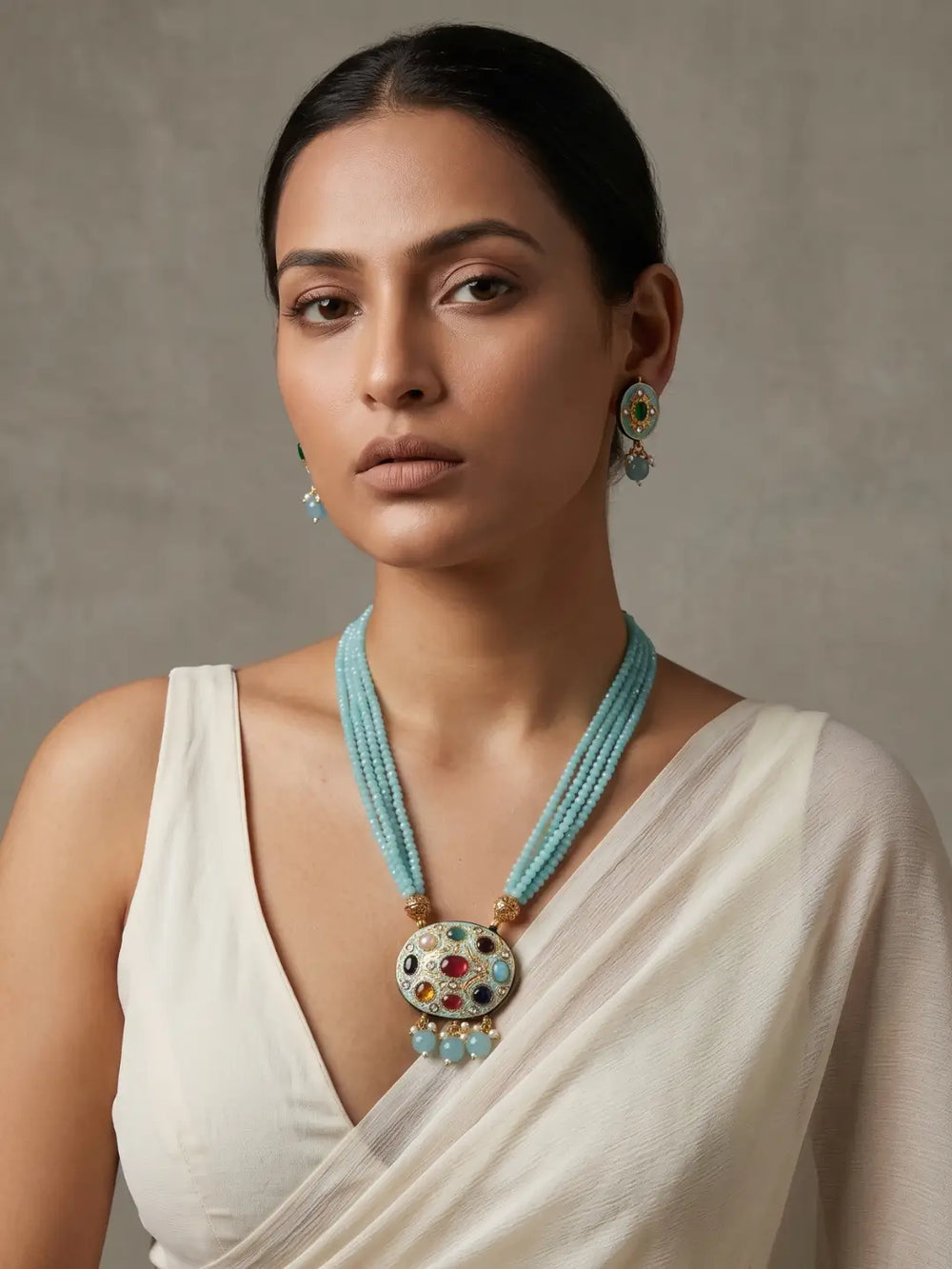 Gold-plated sky blue necklace featuring a Navratna Meenakari pendant, layered beads and matching stud earrings.