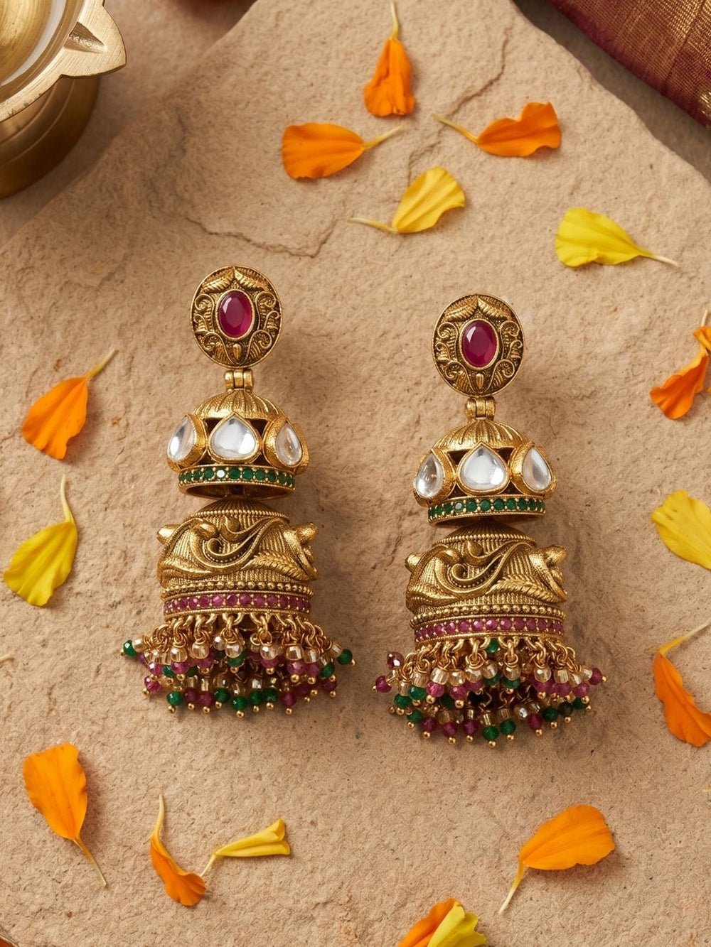 Statement antique gold double Jhumka earrings with Kundan detailing, ruby stone accents and decorative bead tassels for ethnic outfits.