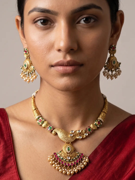 Traditional antique gold finish floral necklace set with green and pink stones, Kundan details and matching earrings for wedding styling