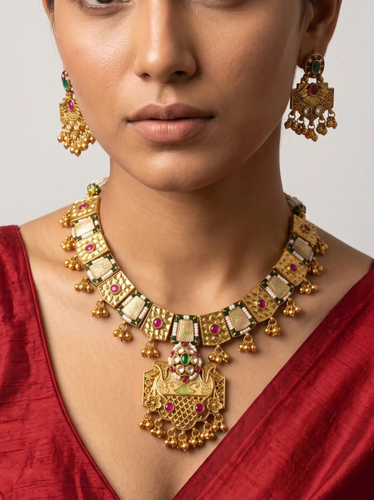 Traditional antique gold necklace with Kundan detailing, colourful Meenakari accents, red and green stones and matching earrings.