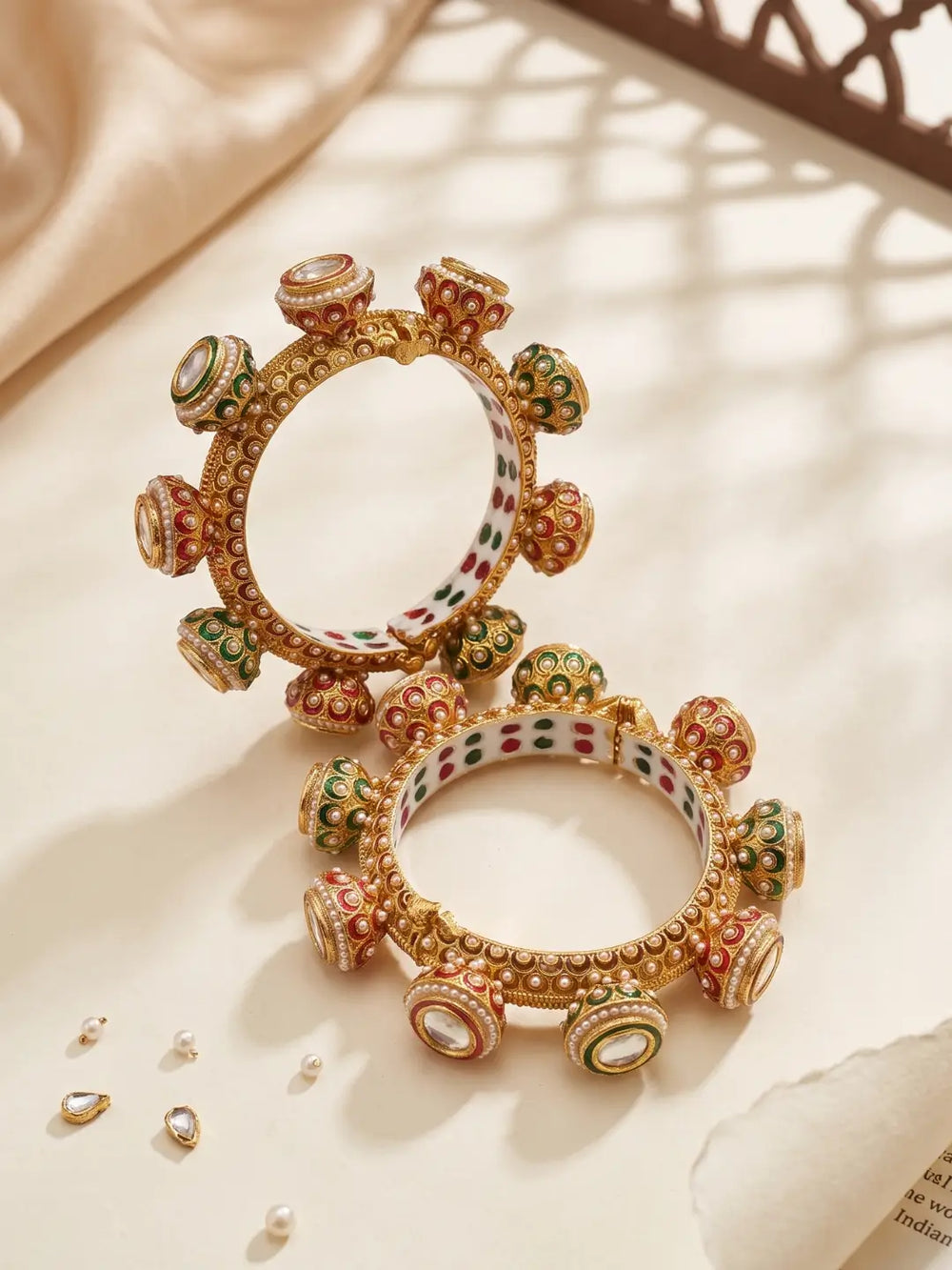 Traditional Meenakari Kundan Gokhru kada bangles with pearl accents, red and green detailing and gold plating for bridal and wedding outfits.