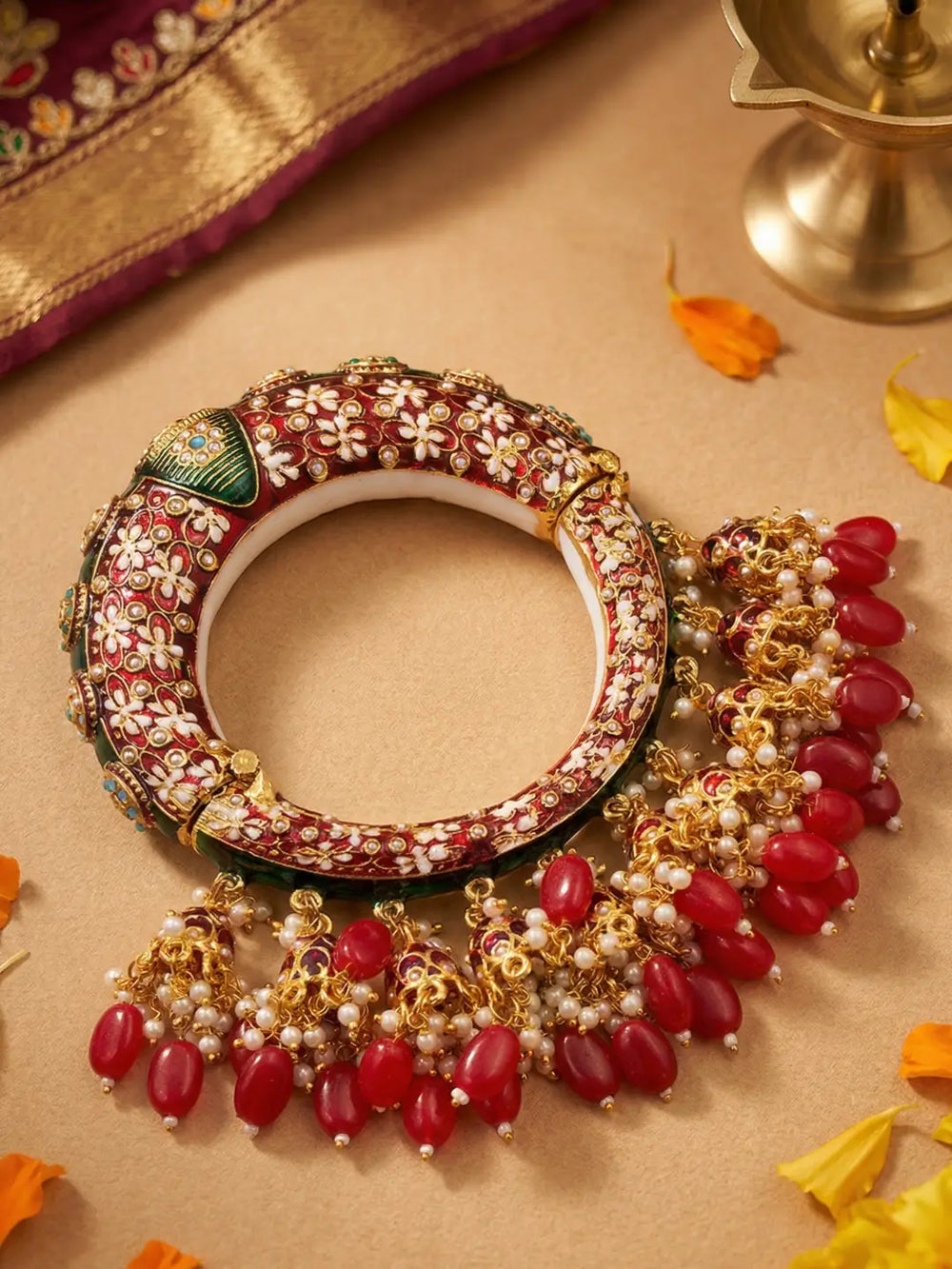 Traditional red Meenakari Kundan kada bangle with floral motifs, stone accents and hanging jhumka details for saree and lehenga styling.