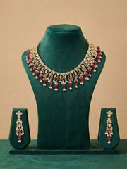 ruby red polki kundan Jewelry set with necklace and earrings on a green mannequin against a beige background