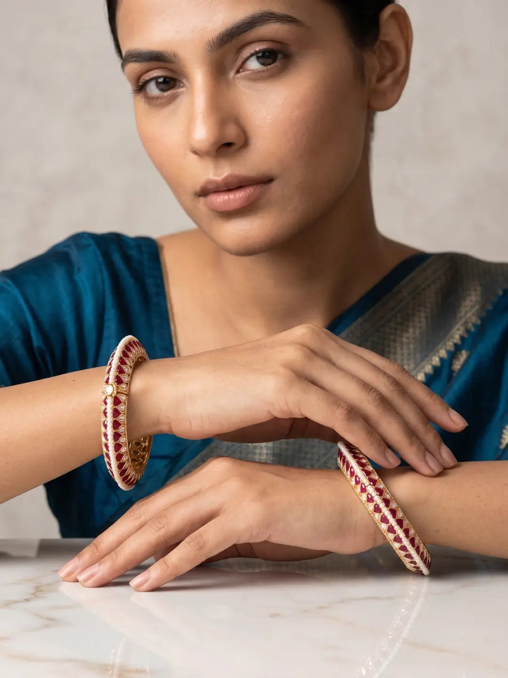 a women is wearing a handcrafted gold-plated Kundan bangles featuring sparkling Kundan stones, elegant pearl borders, and ruby red enamel detailing, perfect for bridal wear, weddings, festive occasions, and traditional Indian jewellery.