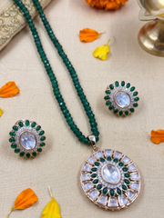 A green beaded Kundan jewelry set featuring a round pendant necklace, a matching stud earring, arranged on a beige fabric background with orange flower petals.
