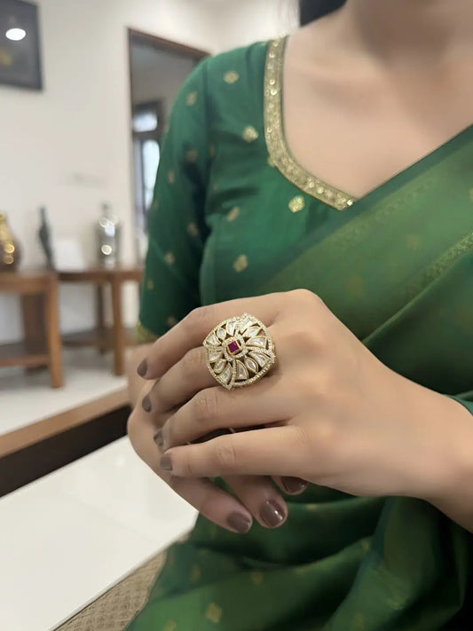 Person wearing a green saree with a square-shaped kundan ring on a blurred indoor background