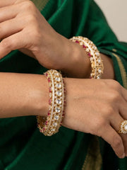Close-up of hands of a women wearing gold plated studded ruby and kundan bangle on her both wrists