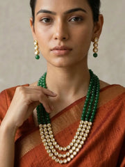 A women wearing a Gold Plated Layered Kundan and green stones Beaded Necklace Set on a saree