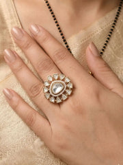 Close-up of a hand wearing a polki ring with a heart-shaped center on a beige fabric background.