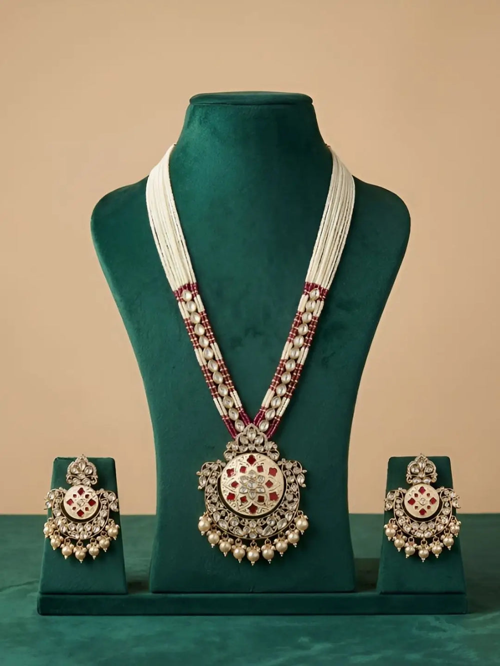 Jewelry set with necklace and earrings on a green mannequin against a beige background