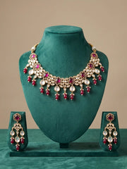 Gold-toned Indian Kundan jewelry set featuring a statement necklace and matching drop earrings displayed on a teal velvet jewelry bust.