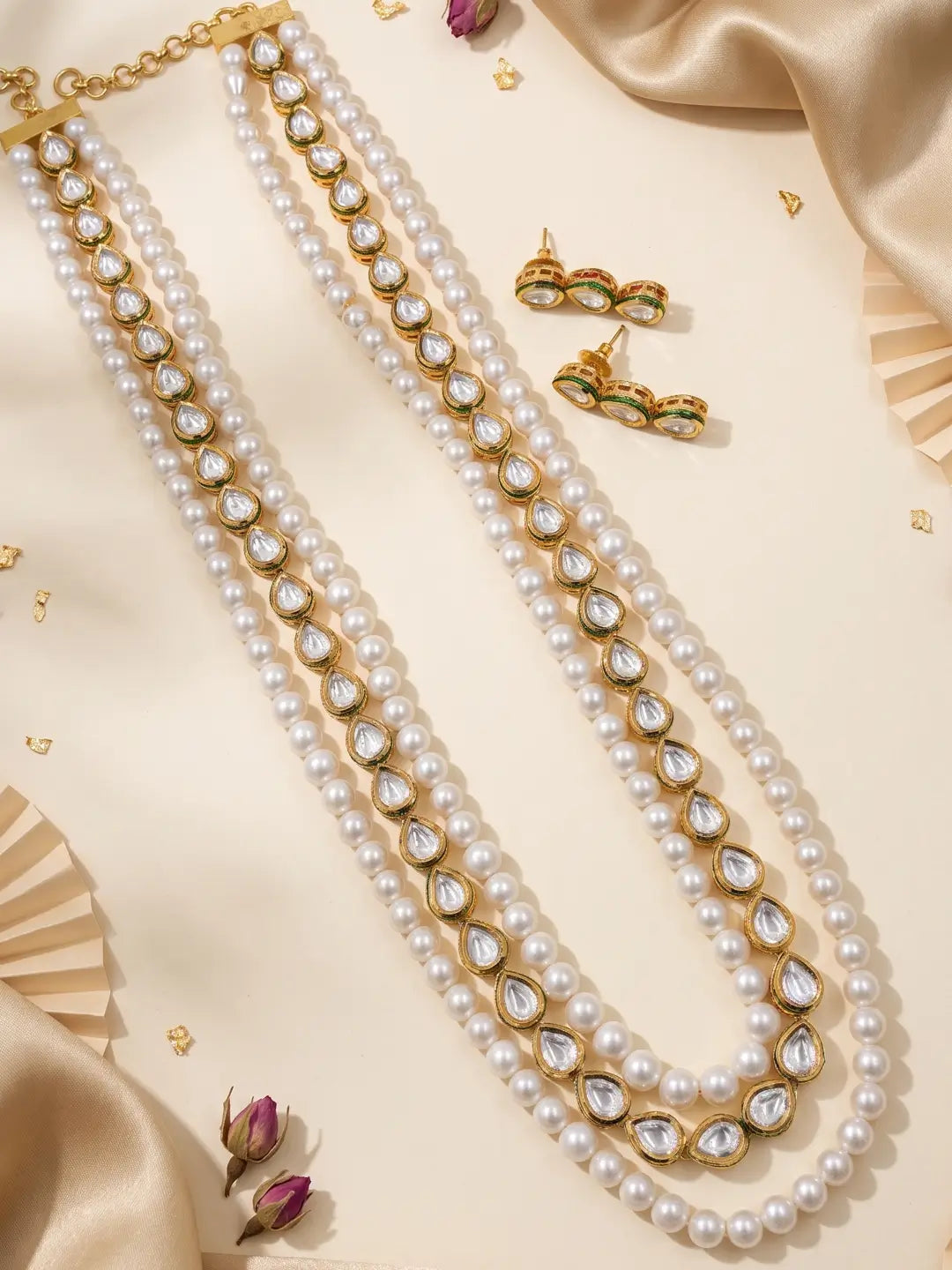 Back view of the adjustable dori of a long white pearl and kundan necklace, shown beside the two round pearl strands that sit along the neckline