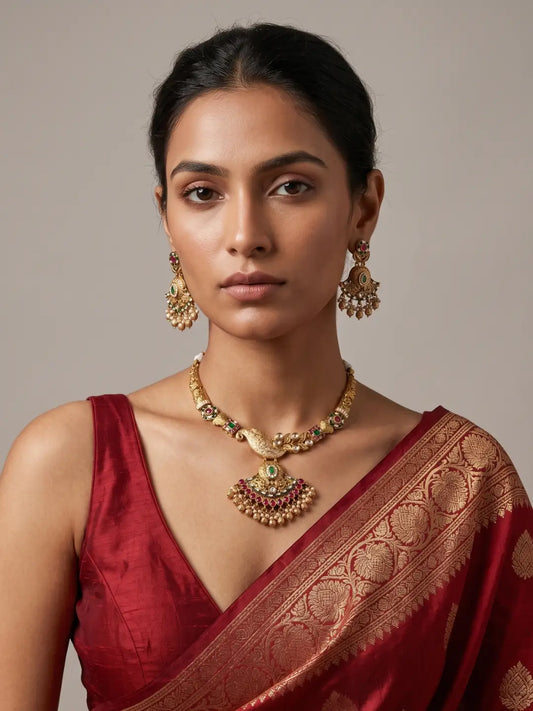 Antique gold finish wedding necklace featuring floral motifs, green and pink stones, white Kundan accents and layered ornamental details