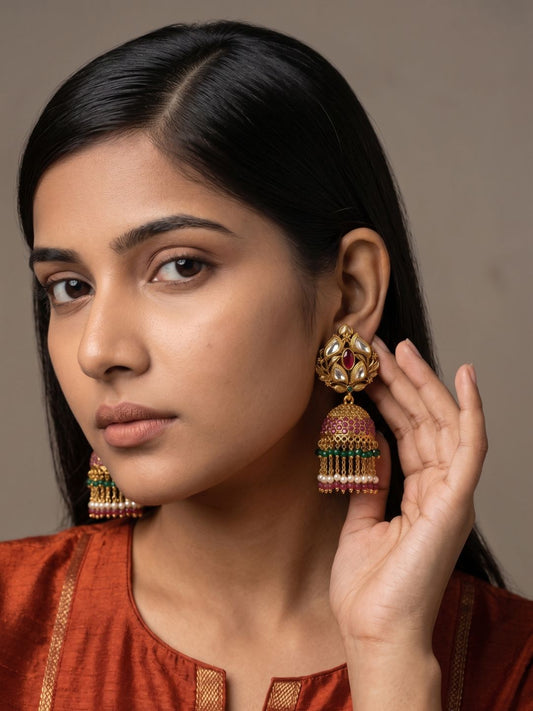 Antique gold Kundan Polki jhumka earrings with a ruby centre, floral detailing, pearl fringe and green bead tassels