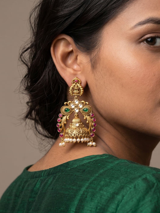 Antique gold Lakshmi Temple Jhumka earrings with goddess Lakshmi and peacock motifs, Kundan stones, ruby accents and pearl drops.