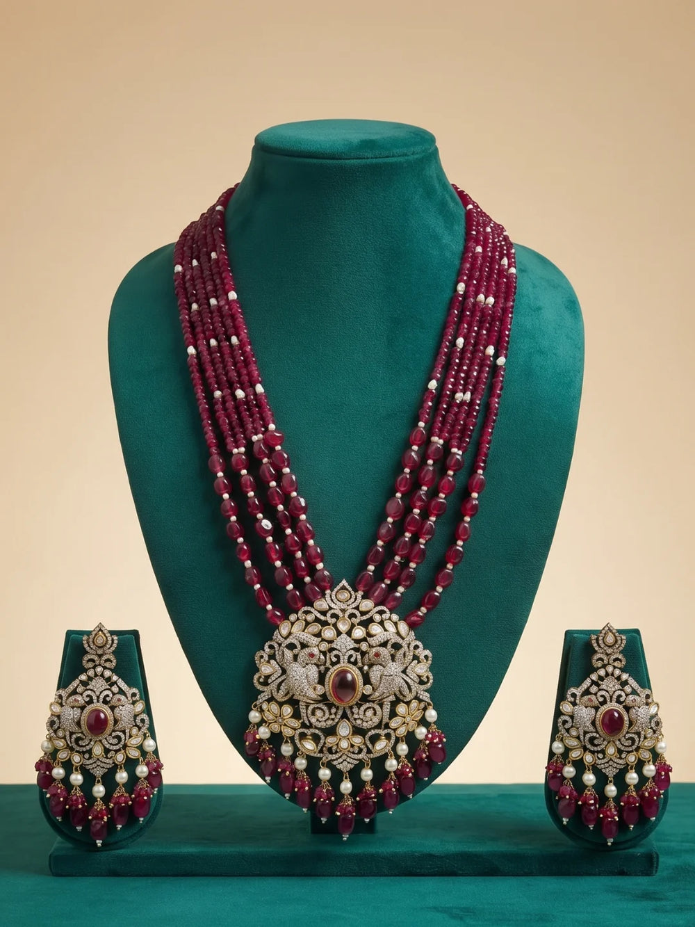 Antique-style necklace set featuring a prominent red centre stone, intricate peacock motifs, white Polki and CZ accents, red beads and pearl details.