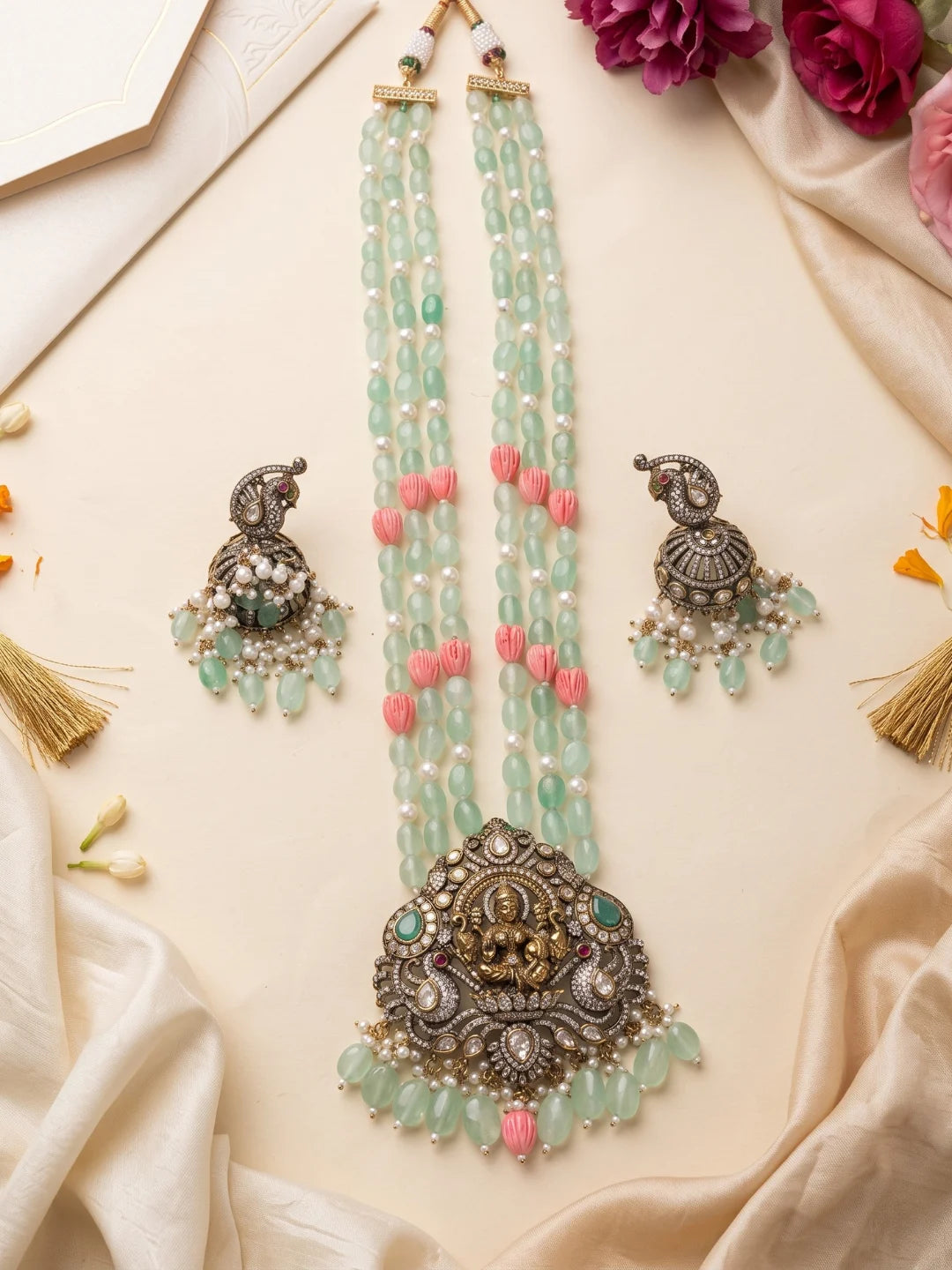 Traditional mint green temple jewellery set with a detailed Lakshmi pendant, decorative stonework, multistrand beads and coordinated jhumka earrings.
