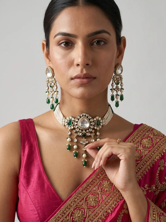 Woman wearing an antique Victorian Polki choker necklace with green stone accents, pearl detailing, an ornate central motif and matching long drop earrings.